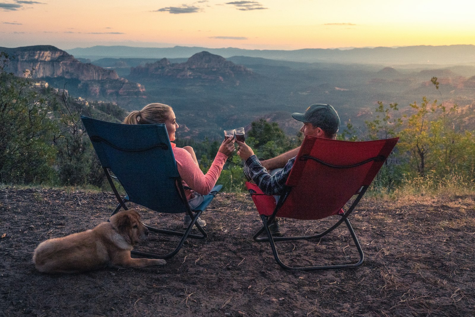 zwei Personen sitzen auf Campingstühlen und schauen auf die Berge