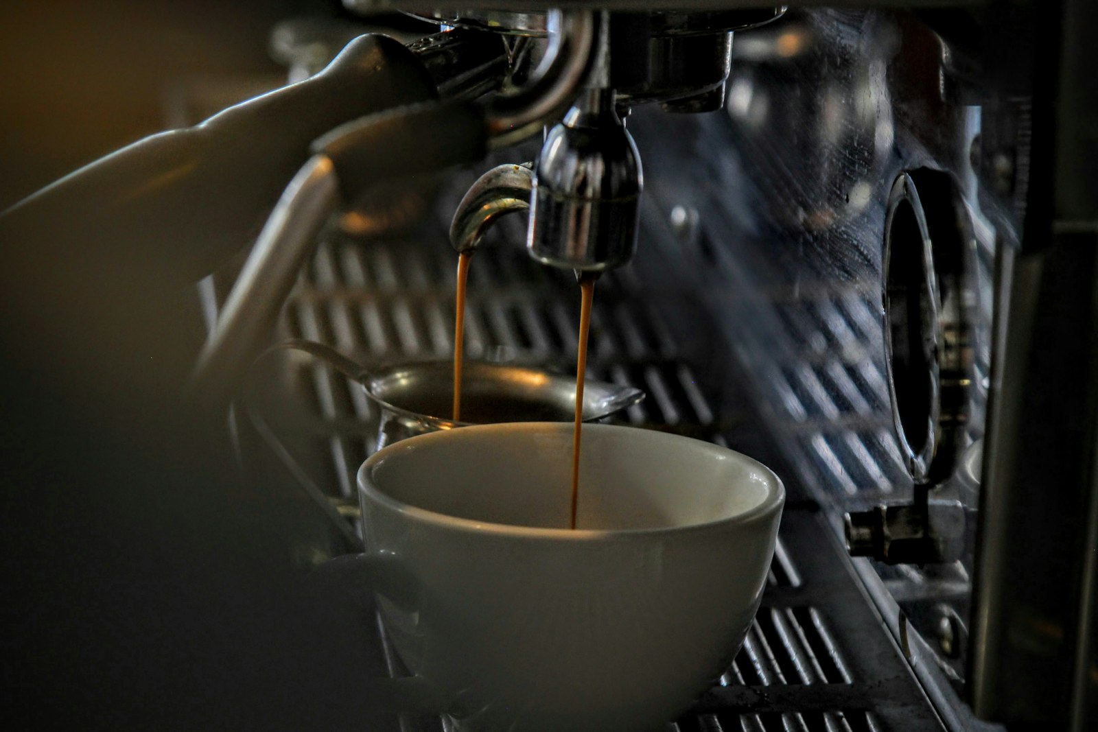 Espresso tropft aus einer Edelstahlmaschine in eine Porzellantasse